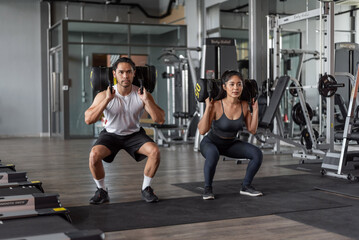 Asian woman and asian man exercise in fitness. Healthy couple doing squat exercise together in gym.