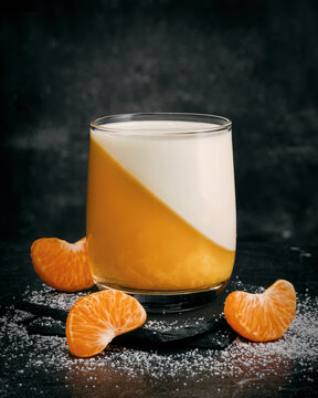 Glass of Tangerine panna cotta dessert with mandarin slices.