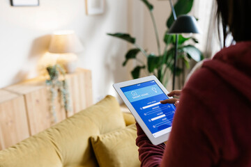 Young woman adjusting lighting equipment through tablet PC at home