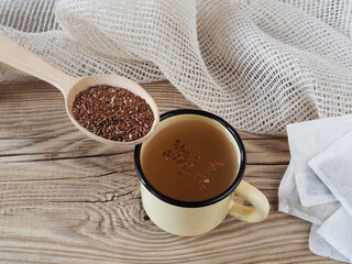 Herbal tea drink, linseed in wooden spoons, tea filter bags on wooden background, top view, flat...