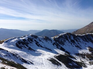 Fototapeta premium Snowy mountain peaks and a blue sky at the background. Snowy mountain surface. Scenic view on Rosa Peak, Sochi. Mountain ridge. Snowy landscape, wintertime. Cold. Peak