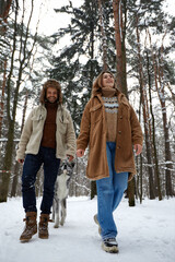 Fototapeta na wymiar Portrait of a young beautiful couple of European appearance with a husky dog in the winter forest