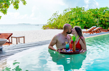 Fototapeta na wymiar young couple newlyweds spend time together in honeymoon admiring in swimming pool with served floating tray drinks and snacks on tropical island resort in Maldives, cocktails and canapes, luxury hotel
