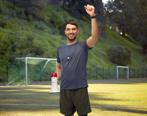 sport, football and people concept - happy smiling male coach or referee with whistle and megaphone celebrating success over soccer field background © Syda Productions