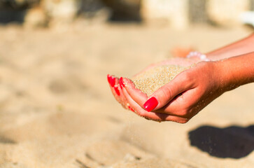 Fototapeta na wymiar a handful of sand in the hands of a girl