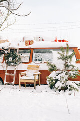 Snow covered van in winter camp, with Christmas decoration.
