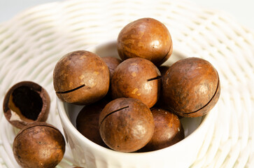 A bunch of macadamia nuts on a light background in a plate