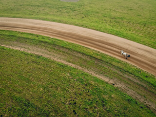 Drone shot of a stallion galloping around the hippodrome and a jockey in two-wheeled cart;...