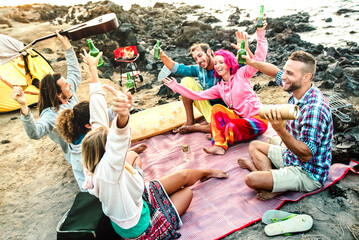 Fototapeta na wymiar Alternative friends having fun together at beach camping party - Life style travel concept with happy people travelers toasting and drinking bottled beer at summer surf camp - Bright multicolor filter
