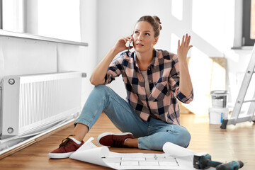 repair, people and real estate concept - angry woman with blueprint and pencil sitting on floor at...