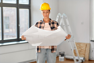 repair, building and real estate concept - woman in helmet with blueprint sitting on floor at home