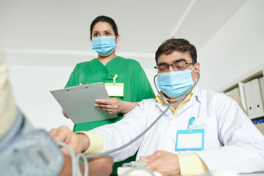 General Practitioner Checking Blood Pressure Of Patient When Medical Nurse Taking Notes In Medical History