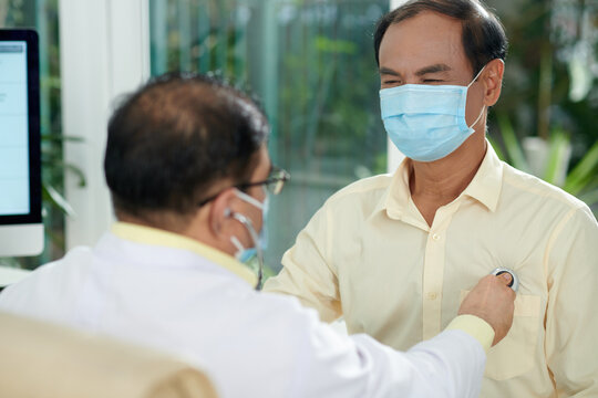 Smiling Senior Man In Medical Mask Visiting Doctor For Annual Checkup And Getting Checked For Shortness Of Breath