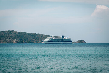 Large white cruise liner sails the turquoise Andaman sea; seascape; luxury tourism concept.