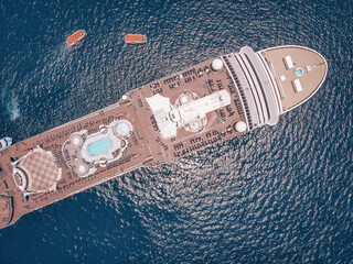 Large luxury cruise ship in the blue waters of the Andaman sea, 2 boats around; aerial view.