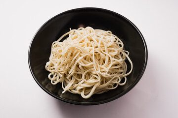 Asian noodles in a black plate on a white background. Asian instant noodles
