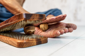 Practice of standing on nails. Sadhu wooden board with nails for sadhu practice. Man massaging his foot with a wooden massager after practicing standing on nails
