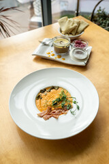 Creamy pumpkin soup with toasted bacon pieces garnished with pumpkin seeds. Healthy low calorie soup and low-fat pate in a glass jar on a wooden table