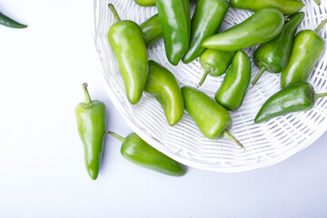 green jalapeno peppers in a white wicker basket on a light background