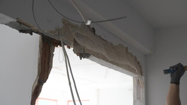 Man hitting a wall trying to remove a lintel during apartment remodeling