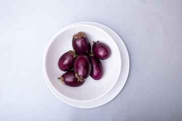 
mini eggplants on a light background on a table in a white plate
