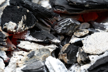 Glowing charcoals in a rusty barbecue grill. View diagonally from the front. Pattern.