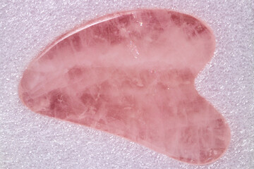 Natural Gua Sha Rose quartz stone on glittering background. Guasha Massage Tool alternative therapy to improve circulation. Face stone massage. Chinese healing method to better health.