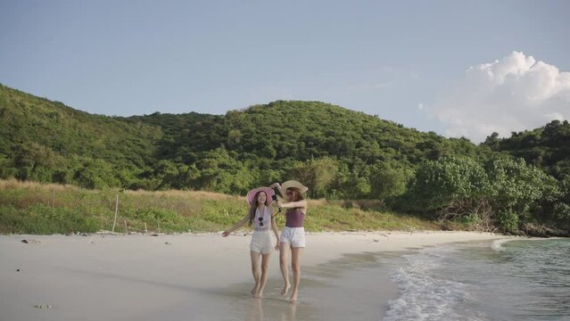 Two beautiful Asian bloggers or vlogger woman happily records and talk with camera about the beautiful nature of the sea, beach. Social media or content creators share happiness with people.