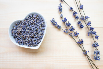 Dried lavender flowers in a bowl on a wooden background. Top view, place for text.