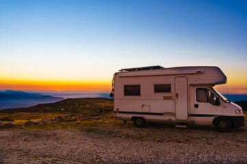 Rv camper in mountains above clouds at sunset