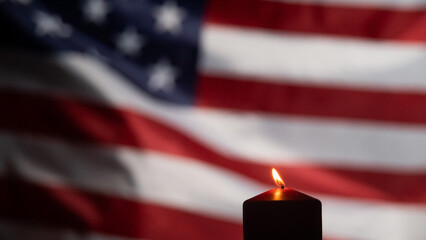 Burning candle against the background of the waving flag of the united states of america in the dark.