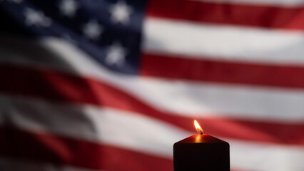 Burning candle against the background of the waving flag of the united states of america in the...