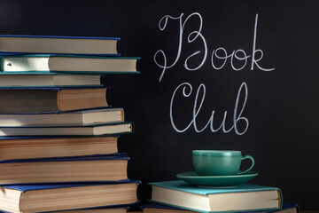 Book Club Concept. A stack of hardcover books with a cup of coffee and chalk lettering on a...