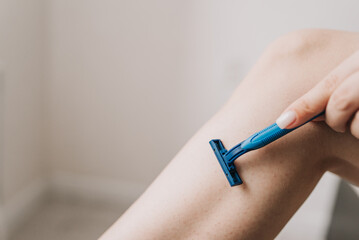 shaving legs with a blue razor