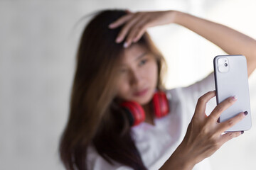 Cute Asian girl holding a cell phone taking a selfie.