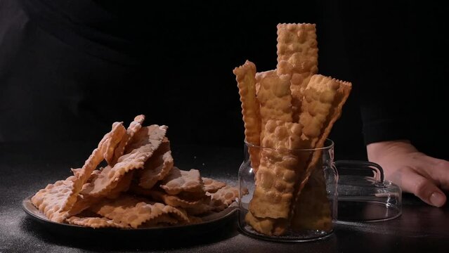Sfrappole or chiachiere or angel wings. Carnival food TYPICAL. Traditional sweet crisp pastry deep-fried and sprinkled with powdered sugar.crispy dessert festive in female hands. 4k