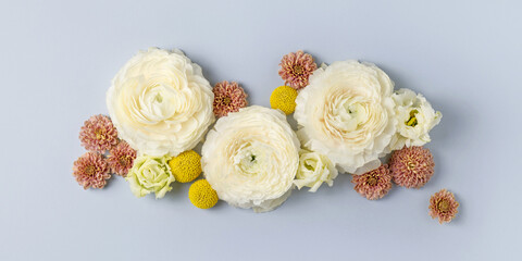 Fototapeta na wymiar Pastel fresh white, pink and yellow flowers on light blue background. Tender floral composition. Blossom spring banner. Holiday postcard. Ranunculus, chrysanthemum, lisianthus. Top view, flat lay.