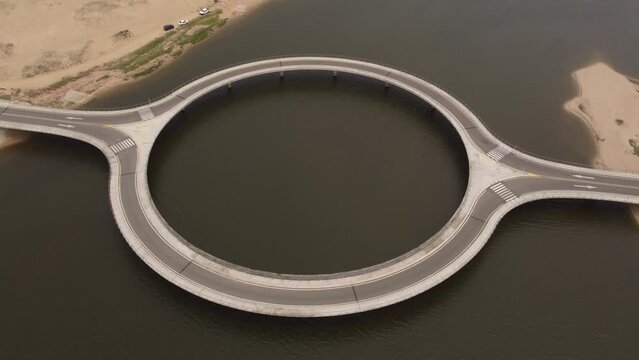 Unusual circular shape of Laguna Garzon Bridge, Uruguay. Aerial forward tilt down