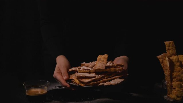 Carnival food TYPICAL and aromatic coffee.Sfrappole or chiachiere or angel wings. Traditional sweet crisp pastry deep-fried and sprinkled with powdered sugar.crispy dessert festive in female hands.4k