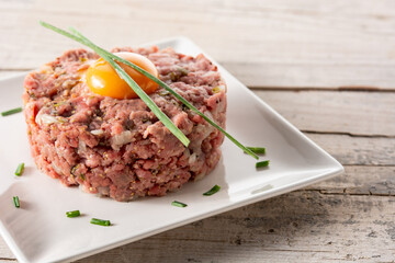 Beef steak tartare on rustic wooden table. Copy space