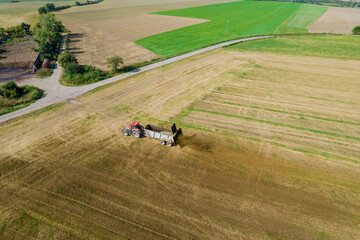 The tractor scatters manure from the trailer in the field. Work in the field near the road. Countryside.