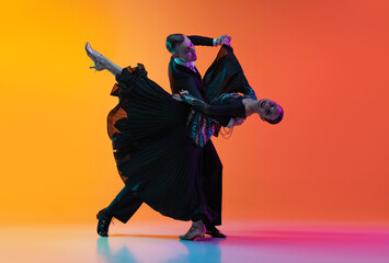 Full-length portrait of young beautiful man and woman dancing ballroom dance isolated over gradient...