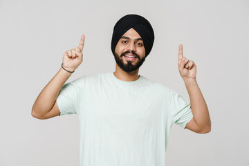 Fototapeta premium Bearded south asian man wearing turban pointing fingers upwards