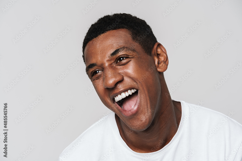 Wall mural Young black man in t-shirt laughing and looking at camera