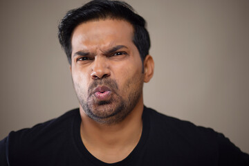 Fototapeta premium Close-up portrait of a disappointed angry young man against dark background