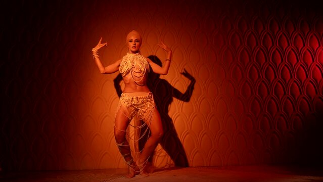 attractive half-naked woman is dancing exotic oriental dance in dark room of royal palace