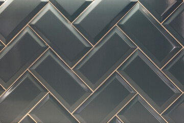 Herringbone decorative tiles. Glossy gray finishing material. Front view. Background. Space for text.