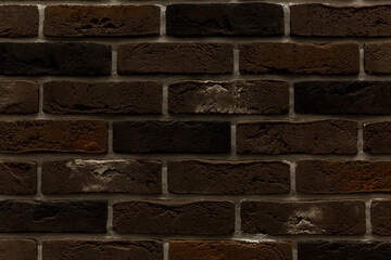 The surface of a dark brown brick wall. Decorative facing tiles. Background. Space for text.