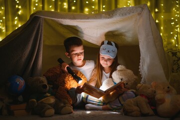 Obraz na płótnie Canvas Little children reading bedtime story at home