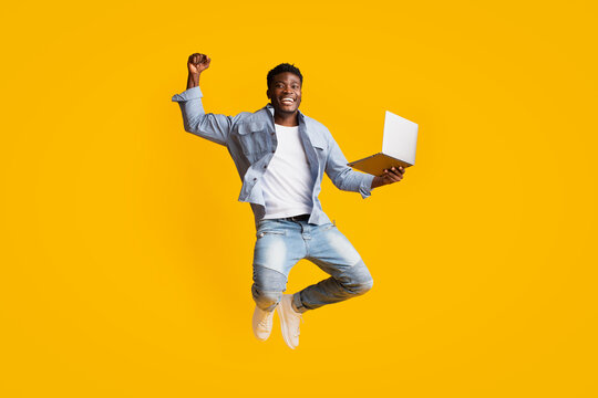 Cheerful African American Guy Holding Laptop And Jumping Up